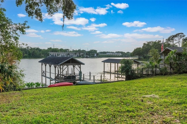 view of dock featuring a water view, a lawn, and boat lift