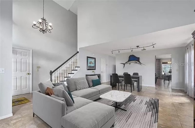 living area with rail lighting, stairs, an inviting chandelier, baseboards, and a high ceiling