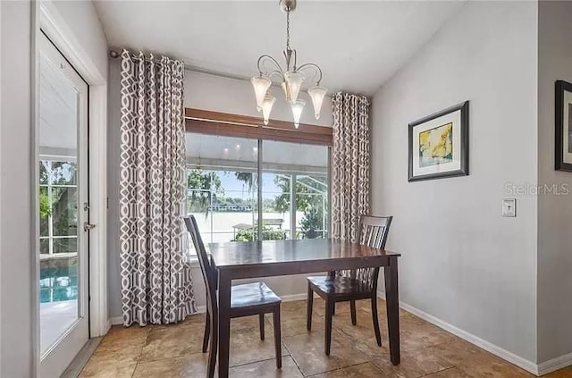 dining room featuring baseboards, a water view, and a chandelier