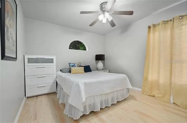 bedroom with a ceiling fan, baseboards, and light wood-type flooring