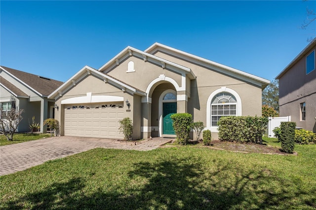 view of front of house with a front lawn, decorative driveway, an attached garage, and stucco siding