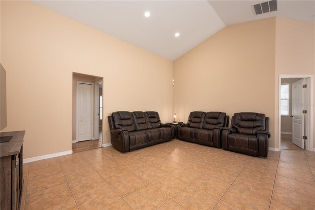 living area with light tile patterned floors, high vaulted ceiling, and visible vents