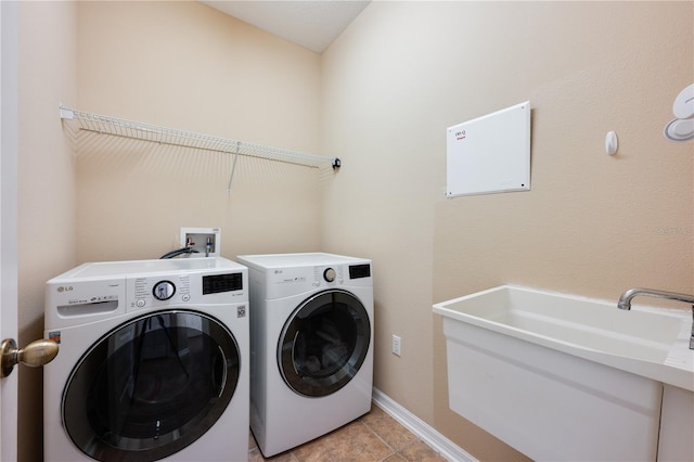 washroom with laundry area, light tile patterned floors, baseboards, washing machine and clothes dryer, and a sink