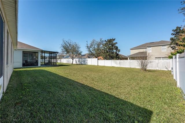 view of yard with a sunroom, a fenced backyard, and a residential view