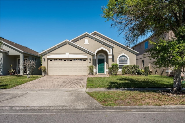 view of front of house with a front yard, decorative driveway, an attached garage, and stucco siding