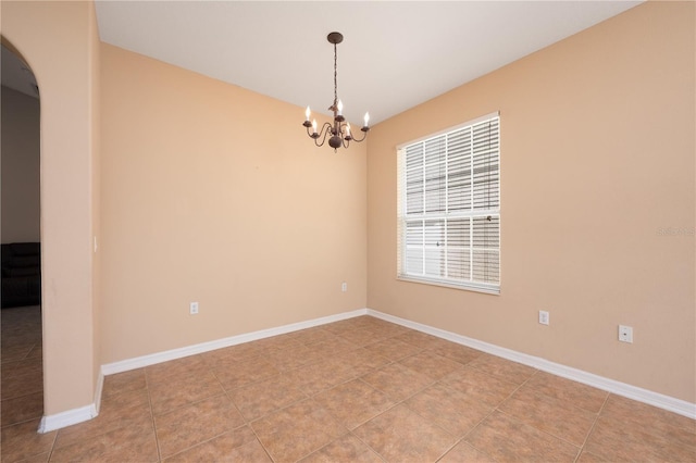 empty room featuring a chandelier, tile patterned flooring, and baseboards