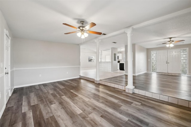 unfurnished living room featuring decorative columns, dark hardwood / wood-style floors, and ceiling fan