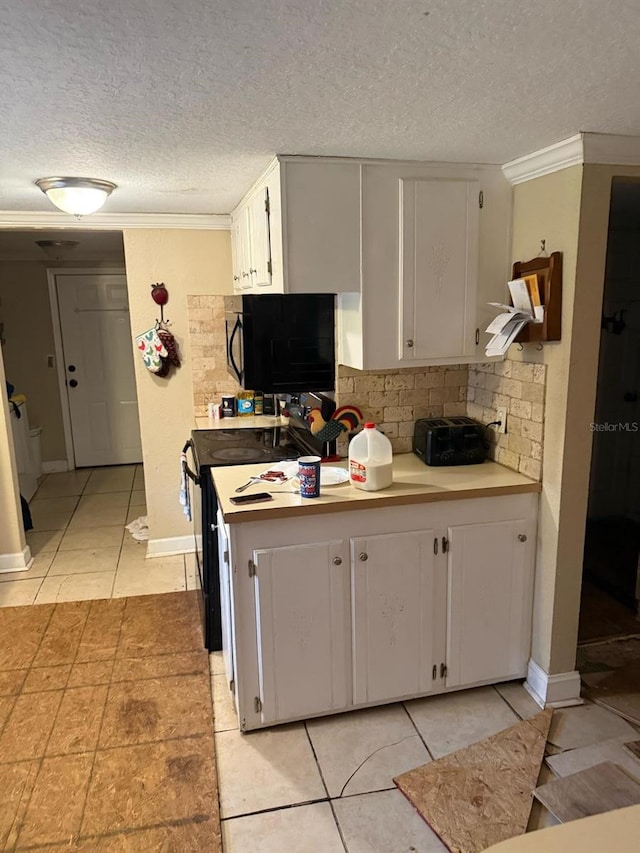 kitchen with white cabinets, decorative backsplash, light tile patterned floors, black appliances, and crown molding