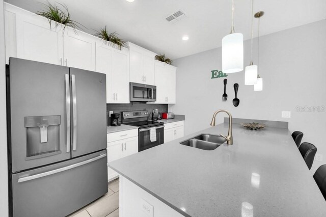 9017 Dogleg Dr, Davenport, FL 33896 - kitchen with visible vents, appliances with stainless steel finishes, a peninsula, white cabinetry, and a sink