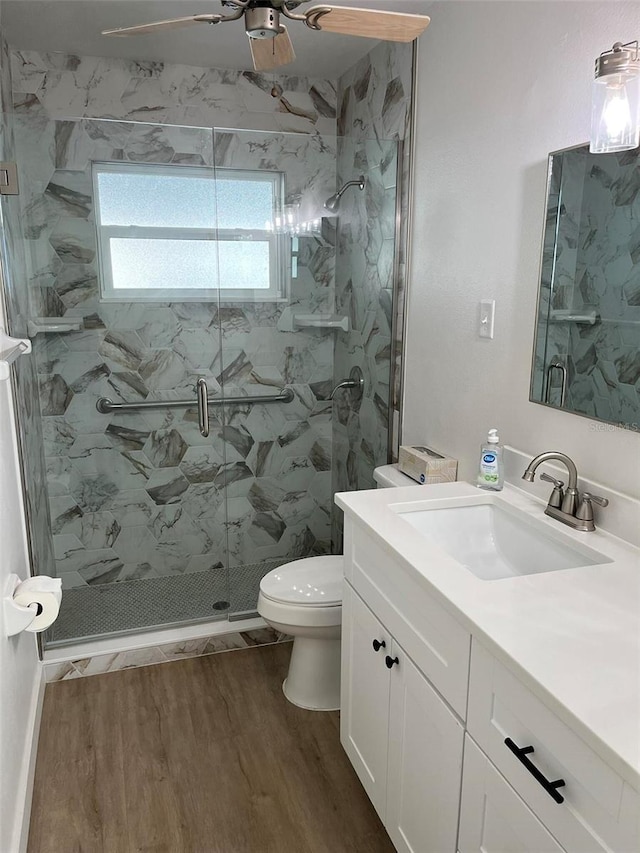 bathroom featuring hardwood / wood-style floors, vanity, walk in shower, ceiling fan, and toilet