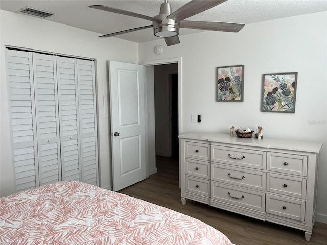 bedroom with dark hardwood / wood-style floors, a textured ceiling, a closet, and ceiling fan