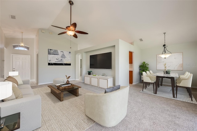 living room featuring high vaulted ceiling, arched walkways, light carpet, and visible vents