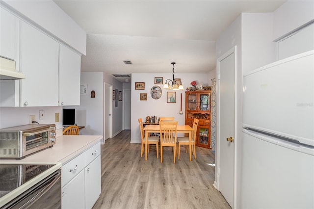 kitchen with a toaster, white cabinets, freestanding refrigerator, light countertops, and pendant lighting