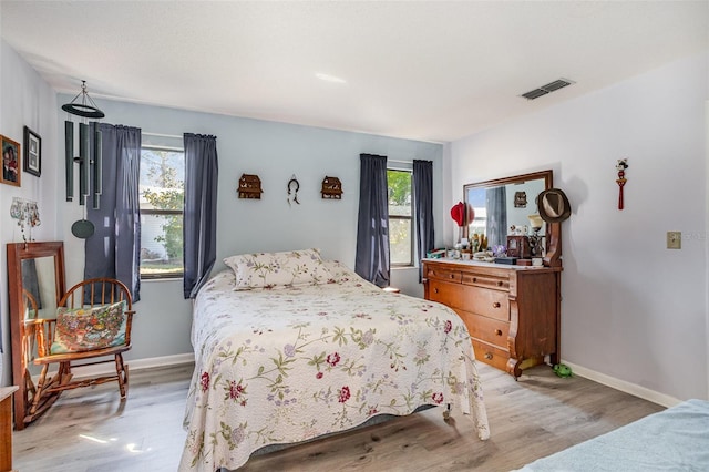 bedroom with light wood-style floors, baseboards, and visible vents