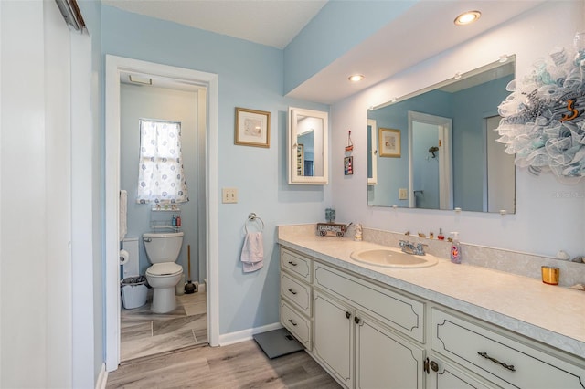 bathroom featuring baseboards, toilet, wood finished floors, vanity, and recessed lighting