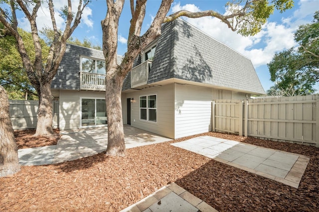 rear view of property featuring a balcony and a patio area