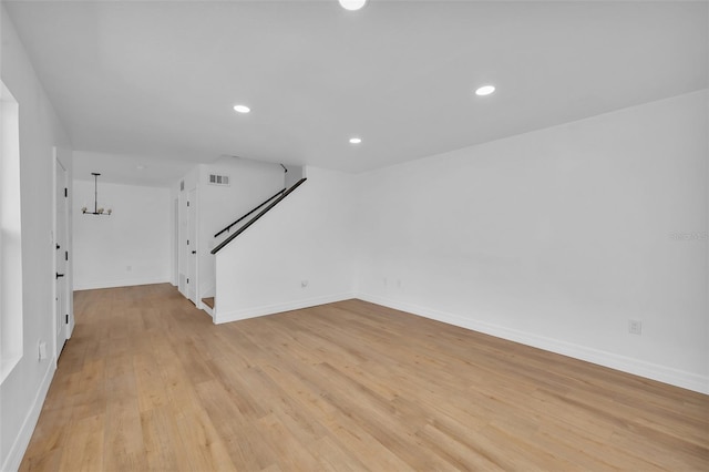 unfurnished living room featuring a chandelier and light wood-type flooring