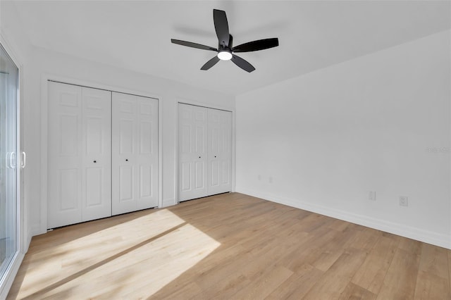 unfurnished bedroom featuring multiple closets, ceiling fan, and light wood-type flooring