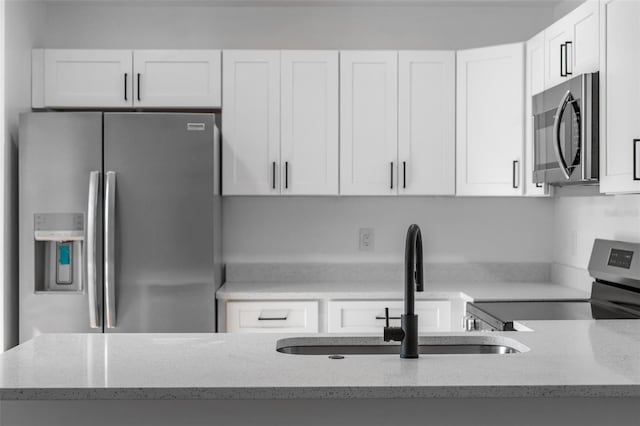 kitchen featuring stainless steel appliances, light stone countertops, and white cabinets