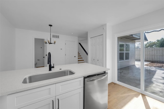 kitchen with sink, hanging light fixtures, light stone countertops, white cabinets, and stainless steel dishwasher