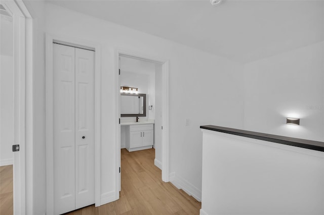 hallway with sink and light wood-type flooring