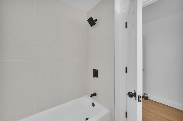 bathroom featuring wood-type flooring and tiled shower / bath