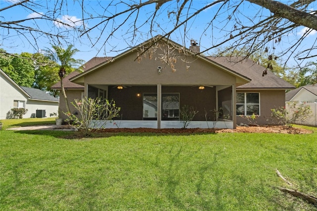 back of property featuring a sunroom, a yard, a chimney, and stucco siding