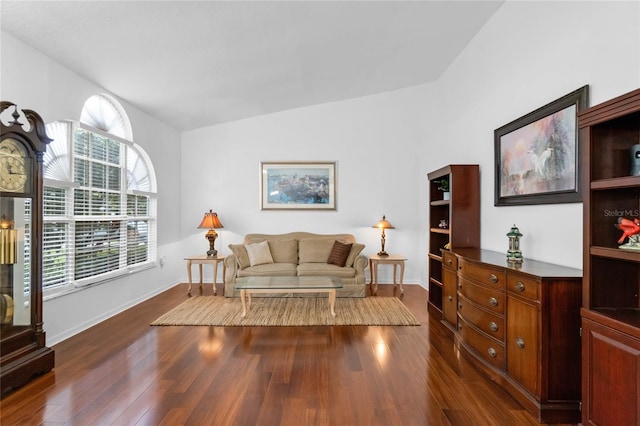 living area with dark wood-style floors, vaulted ceiling, and baseboards