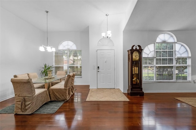 entrance foyer with baseboards, a notable chandelier, and wood finished floors