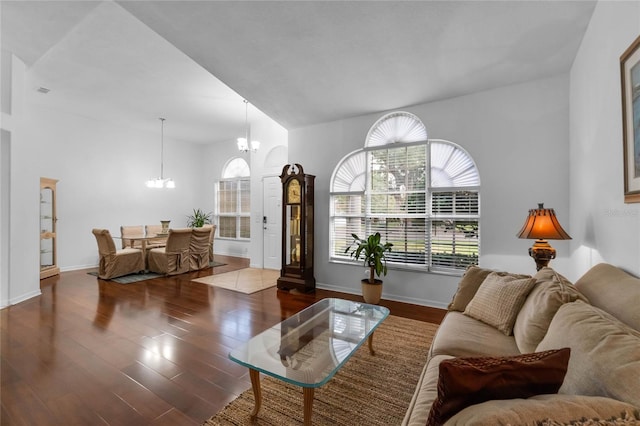 living room featuring baseboards, vaulted ceiling, wood finished floors, and an inviting chandelier