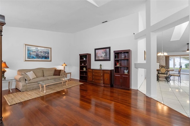 living area featuring baseboards, a high ceiling, wood finished floors, and an inviting chandelier