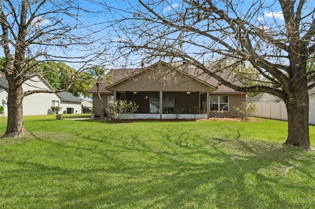 back of property with a sunroom, fence, and a yard