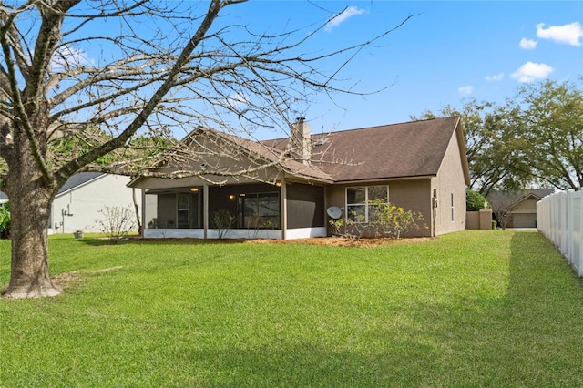 back of house with a lawn, a sunroom, a chimney, fence, and stucco siding