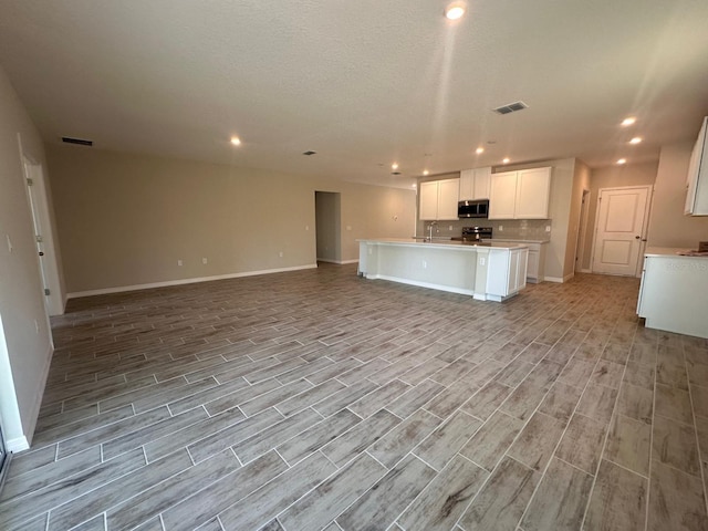 kitchen featuring sink, a center island with sink, white cabinets, and appliances with stainless steel finishes