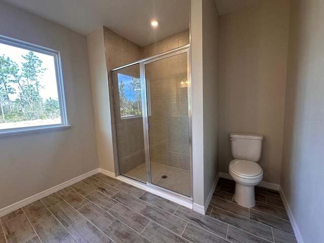 bathroom featuring a shower with door and toilet