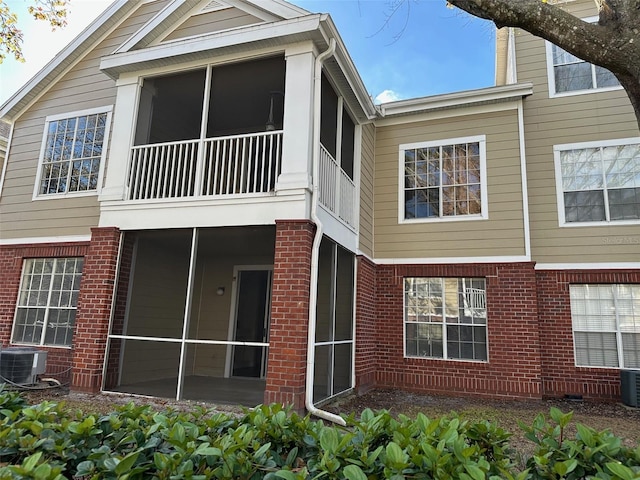 back of property with central AC and a sunroom