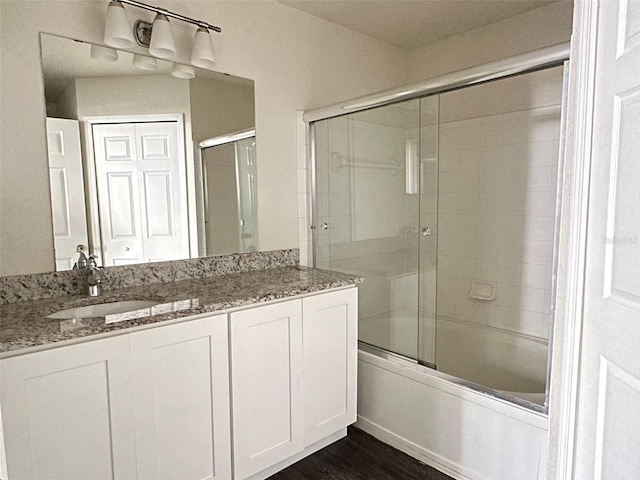 bathroom featuring wood-type flooring, combined bath / shower with glass door, and vanity