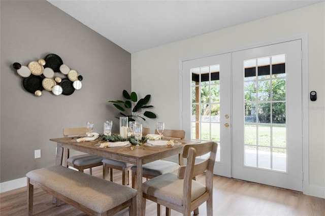 dining area with lofted ceiling, light hardwood / wood-style floors, and french doors