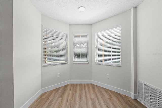 spare room featuring light hardwood / wood-style flooring and a textured ceiling