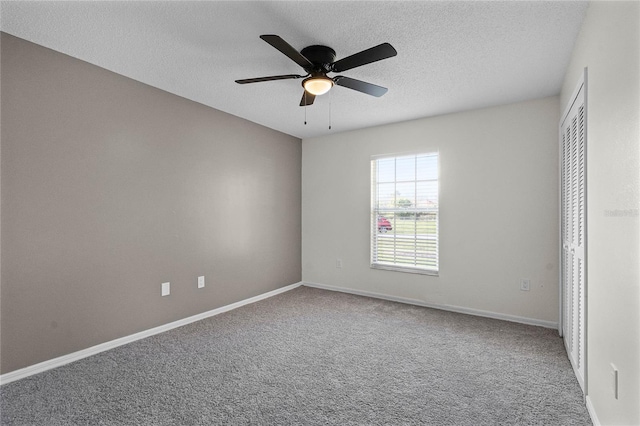 spare room with ceiling fan, a textured ceiling, and carpet