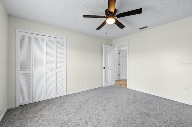 unfurnished bedroom featuring ceiling fan, light colored carpet, a closet, and a textured ceiling