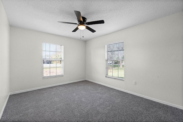 empty room with ceiling fan, dark carpet, and a textured ceiling