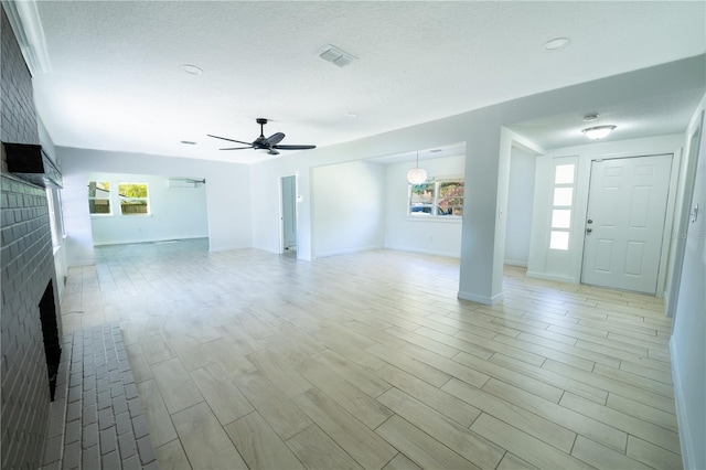 unfurnished living room featuring light wood-style floors, a fireplace, visible vents, and a textured ceiling