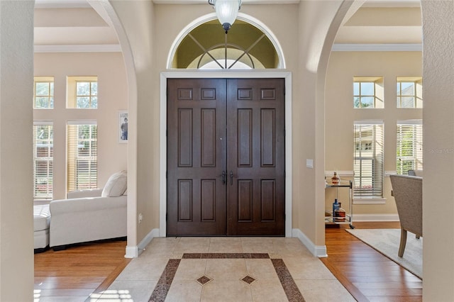 entryway with plenty of natural light, a towering ceiling, and light hardwood / wood-style floors