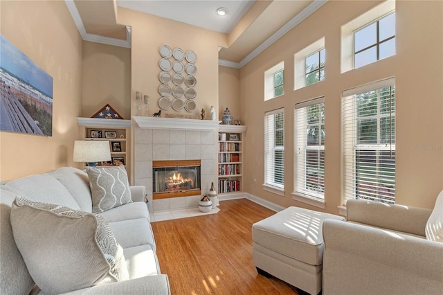 living room with ornamental molding, a fireplace, hardwood / wood-style floors, and a high ceiling