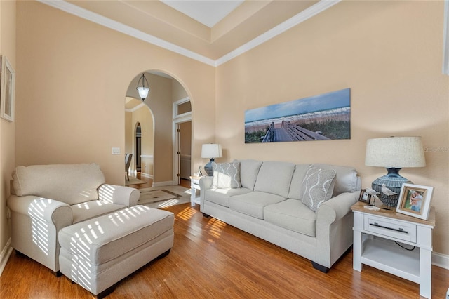 living room with crown molding, hardwood / wood-style flooring, and a towering ceiling
