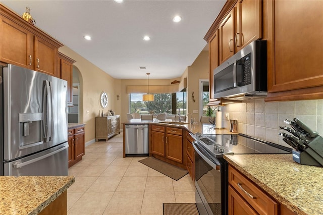 kitchen featuring sink, backsplash, stainless steel appliances, light tile patterned flooring, and decorative light fixtures