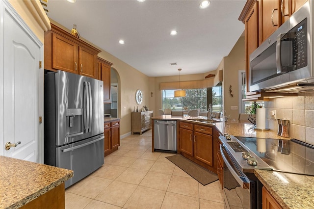 kitchen with decorative light fixtures, sink, decorative backsplash, light tile patterned floors, and stainless steel appliances