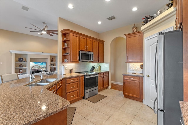 kitchen featuring sink, decorative backsplash, light tile patterned floors, light stone counters, and stainless steel appliances