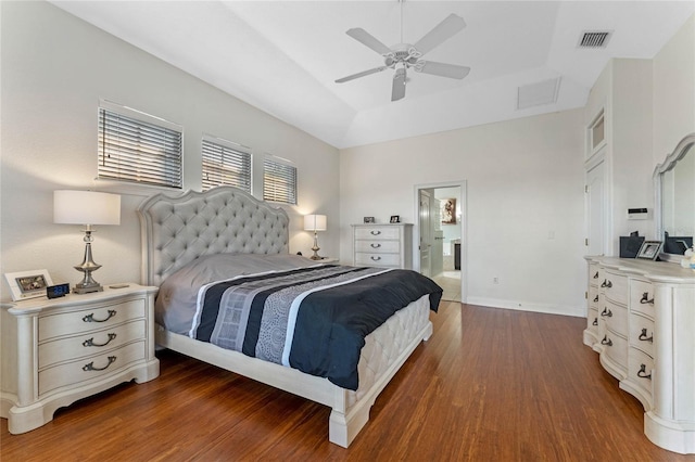 bedroom with ceiling fan, ensuite bath, dark hardwood / wood-style flooring, and a raised ceiling